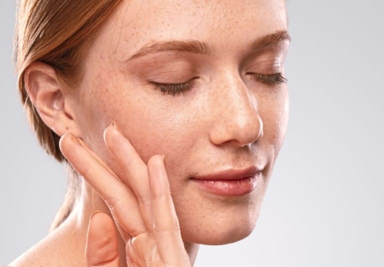 woman touching her cheek after filler